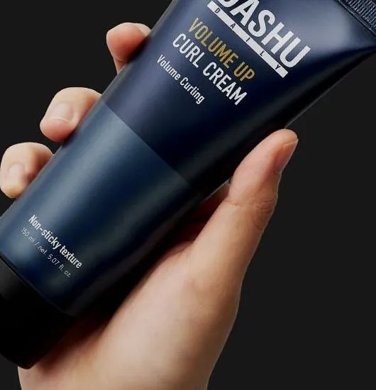 A hand holding a tube of DASHU Daily Volume Up Curl Cream