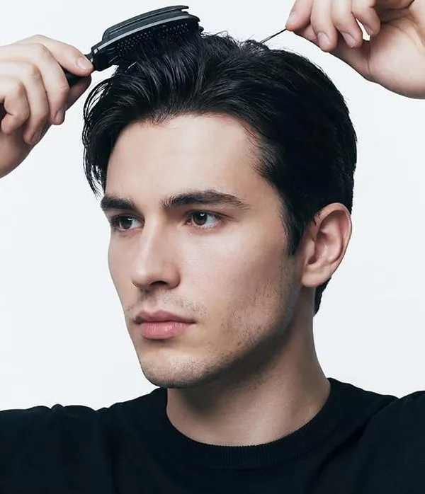 A man lifting the hair at his crown with a DASHU styling pick