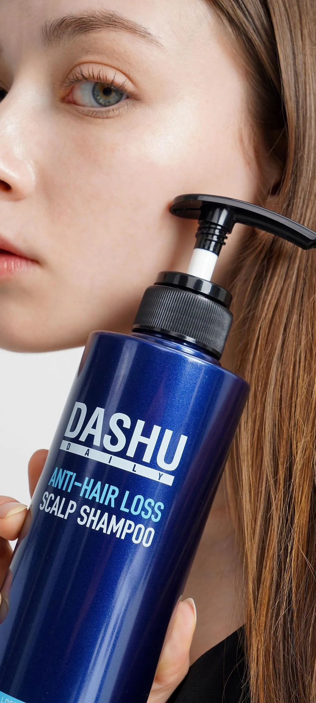 A woman holding a pump bottle of DASHU Anti-Hair Loss Scalp Shampoo
