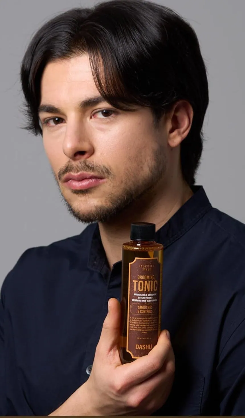 A man with blow-dried volume holding a bottle of DASHU Grooming Tonic